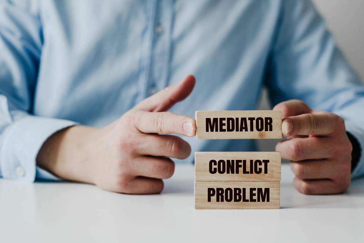 may 7,, businessman in a blue shirt arranges wooden jigsaw blocks with the word conflict mediator problem solving concept using a mediator help during conflicts